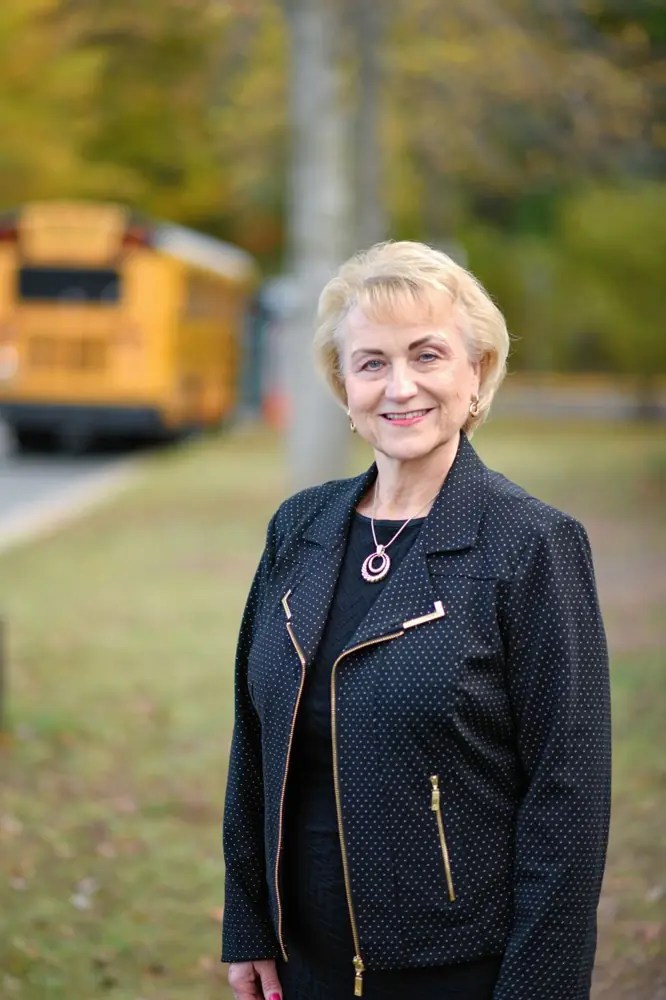 Debbie Kilpatrick standing near a school bus on a fall afternoon