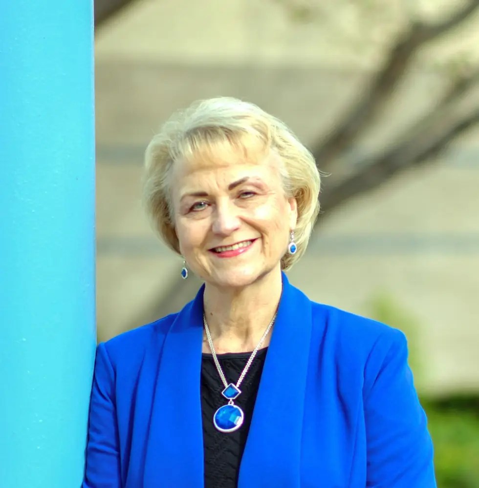 Debbie Kilpatrick smiling beside a bright turquoise pillar